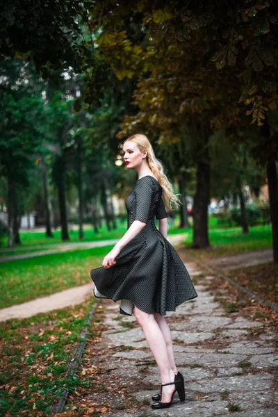 Jovem linda menina loira com batom vermelho em seus grandes olhos brilhantes e torná-lo em vestido posando nas ruas, o pôr do sol roupas da moda — Fotografia de Stock