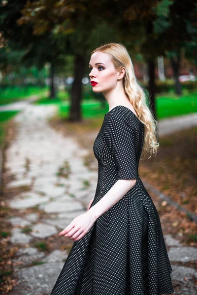 Giovane bella ragazza bionda con rossetto rosso nei suoi grandi occhi luminosi e farlo in abito in posa per le strade, il sole al tramonto vestiti alla moda — Foto Stock