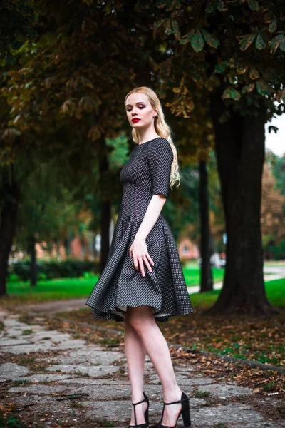 Jovem linda menina loira com batom vermelho em seus grandes olhos brilhantes e torná-lo em vestido posando nas ruas, o pôr do sol roupas da moda — Fotografia de Stock