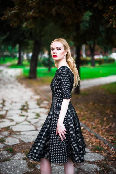 Jovem linda menina loira com batom vermelho em seus grandes olhos brilhantes e torná-lo em vestido posando nas ruas, o pôr do sol roupas da moda — Fotografia de Stock