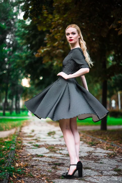 Giovane bella ragazza bionda con rossetto rosso nei suoi grandi occhi luminosi e farlo in abito in posa per le strade, il sole al tramonto vestiti alla moda — Foto Stock