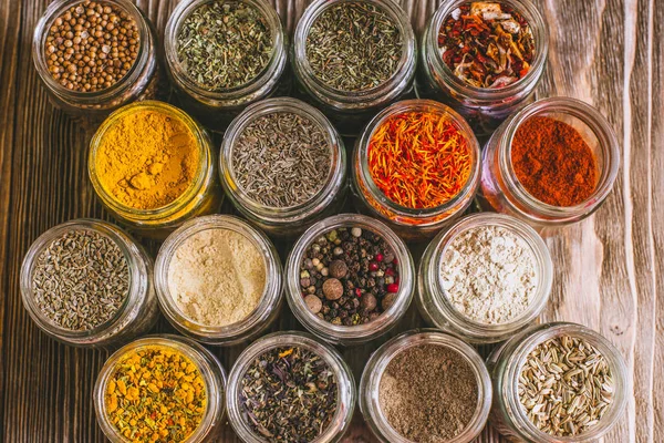 Olika färgglada sorters kryddor på rustika träbord, ovanifrån — Stockfoto