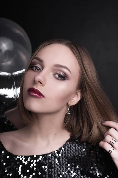 Close up fashion portrait of a young beautiful elegant girl with bright party make up in evening black sequin top. She is keeping silver stars balloons in her hand. Girl at the party. Retouched shot — Stock Photo, Image