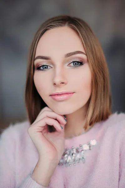 Foto suave de mujer joven fresca en suéter tierno rosa sonriendo. Chica bonita disfrutando de la mañana soleada temprano en casa . — Foto de Stock