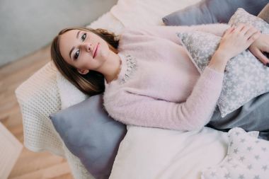 Yumuşak pembe ihale kazak gülümseyen içinde taze genç kadının fotoğrafını. Güzel kız zevk erken güneşli sabah evde.