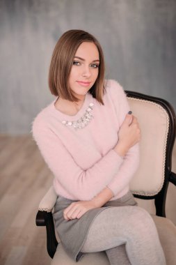 Yumuşak pembe ihale kazak gülümseyen içinde taze genç kadının fotoğrafını. Güzel kız zevk erken güneşli sabah evde.
