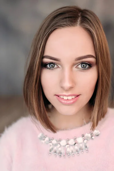 Foto suave de mujer joven fresca en suéter tierno rosa sonriendo. Chica bonita disfrutando de la mañana soleada temprano en casa . — Foto de Stock