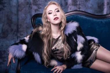 Pullu elbise ve Mavi kürk manto içinde poz çekici genç kadın. Stüdyo imge