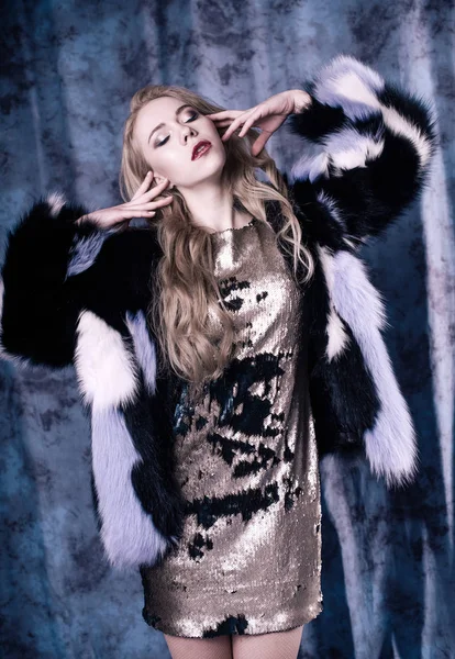 Attractive young woman posing in sequin dress and blue fur coat. Studio image — Stock Photo, Image