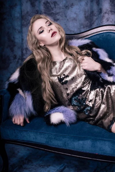 Pullu elbise ve Mavi kürk manto içinde poz çekici genç kadın. Stüdyo imge