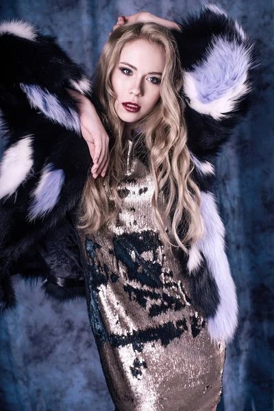 Pullu elbise ve Mavi kürk manto içinde poz çekici genç kadın. Stüdyo imge