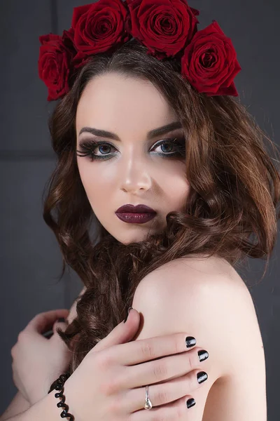Красива молода жінка з трояндами квітка у волоссі. красива дівчина з макіяжем на темному тлі. темно-червоні губи. крупним планом модний ретуш портрет — стокове фото