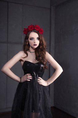 Gül çiçek saç, güzel genç kadın koyu arka plan üzerinde Gotik bir atmosfer makyaj ile siyah elbise giymiş. koyu kırmızı lips.close-up moda düzeltisiz portre