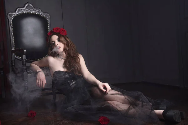 Hermosa joven con flores de rosas en el pelo, vestido negro con maquillaje sobre fondo oscuro, ambiente gótico. rojo oscuro lips.close-up retrato retocado de moda — Foto de Stock