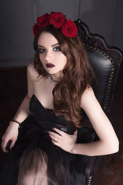 美丽的年轻女子与玫瑰花在头发上，在黑暗的背景，哥特式气氛穿黑裙、 化妆。暗红色的 lips.close 向上时尚润饰画像 — 图库照片