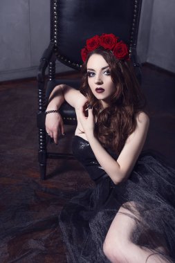 Gül çiçek saç, güzel genç kadın koyu arka plan üzerinde Gotik bir atmosfer makyaj ile siyah elbise giymiş. koyu kırmızı lips.close-up moda düzeltisiz portre
