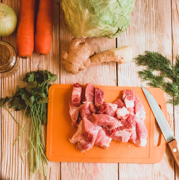 Food ingridients: meat, onion, ginger for recipe stewed beans with meat on wooden background. Steps in cooking, process of preparing food. Concept of homemade healthy food.