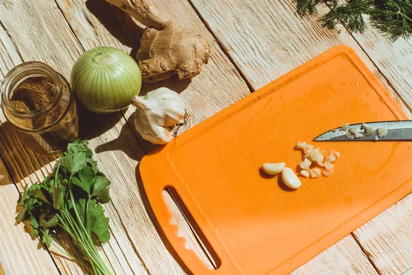 Food ingridients: garlic, onion, ginger for recipe stewed beans with meat on wooden background. Steps in cooking, process of preparing food. Concept of homemade healthy food.