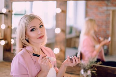 Yakınındaki bir ayna makyaj uygulamak güzel sarışın bir kadın portresi