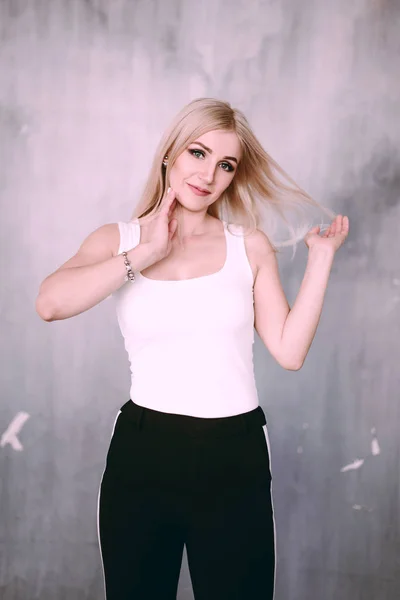 Atrakcyjne pozytywne blond kobieta w średnim wieku noszenie różowa kurtka i spodnie w paski do spodni z uśmiechem piękny pozowanie ścianę oddala, patrząc prosto w kamerę. Mody retuszowane p — Zdjęcie stockowe