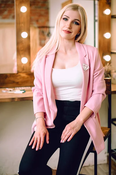 Make-up artist positiva vacker blond kvinna poserar nära spegeln i make-up rum — Stockfoto