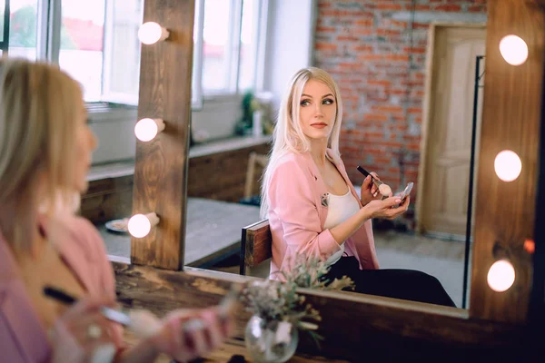 Yakınındaki bir ayna makyaj uygulamak güzel sarışın bir kadın portresi