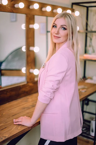 Make-up artist pozitivní krásná blondýnka pózuje u zrcadla v maskérně — Stock fotografie