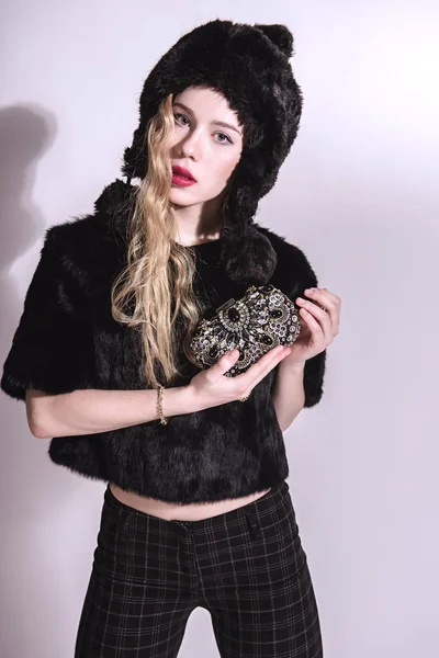 毛皮の帽子と小さな袋を保持している黒のジャケットで美しい若い女性。美しいブロンドの女の子。冬ファッション Beauty.Healthy 髪 — ストック写真