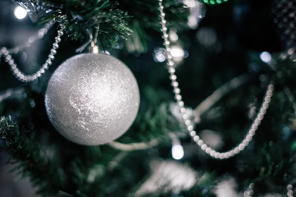 Weihnachtsbaum zu Hause schmücken. Ornament aus nächster Nähe auf dem Hintergrund des Weihnachtsbaums mit bunten Lichtern und Spielzeug, Kopierraum für Text — Stockfoto