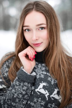 Winter portrait of young beautiful brunette woman wearing sweater. Snowing winter beauty fashion concept. clipart