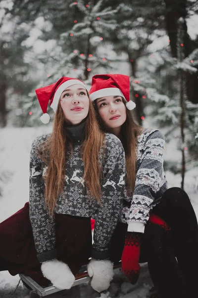 Zwei junge Teenager-Hipster-Freundinnen together.close up Mode Porträt von zwei Schwestern Umarmungen und Spaß im Winter, tragen rote Weihnachtsmützen und Pullover, beste Freunde Paar im Freien, schneebedecktes Wetter — Stockfoto