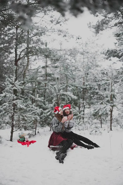 İki genç genç hippi kız arkadaş birlikte. Kırmızı santa şapka ve kazak, en iyi arkadaş çift açık havada giyen iki kız kardeş hugs ve eğleniyor, kış saati, çay içme moda portre kadar kapatın, 
