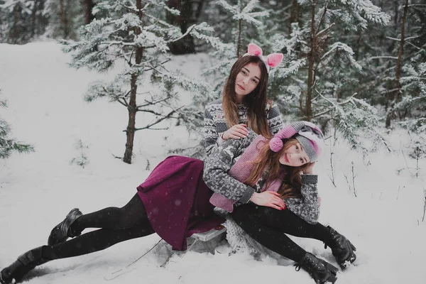 Två unga tonåriga hipster flicka vänner grupp. Stäng upp mode porträtt av två systrar kramar och ha kul vintertid, klädd i rosa hattar, kaninöron och tröja, bästa vänner par utomhus, snöiga — Stockfoto