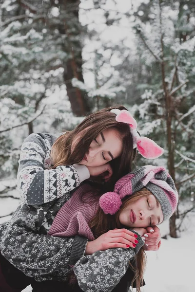 Dos jóvenes amigas adolescentes hipster juntos.Acercamiento retrato de moda de dos hermanas abrazos y divertirse tiempo de invierno, con sombreros rosas, orejas de conejo y suéter, mejores amigos pareja al aire libre, nevado — Foto de Stock