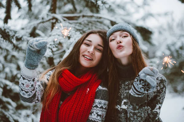 İki genç genç hippi kız arkadaş birlikte. İki kız kardeş hugs moda portre kadar kapatın ve eğleniyor, kazak ve tulum, kış zaman ormanda, maytap tutan arkadaşlarım o çift