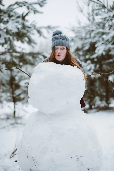 genç genç hippi kız eğleniyor, kazak ve tulum, açık havada, karlı havalarda giyen kış zaman ormanda, kardan adam olun