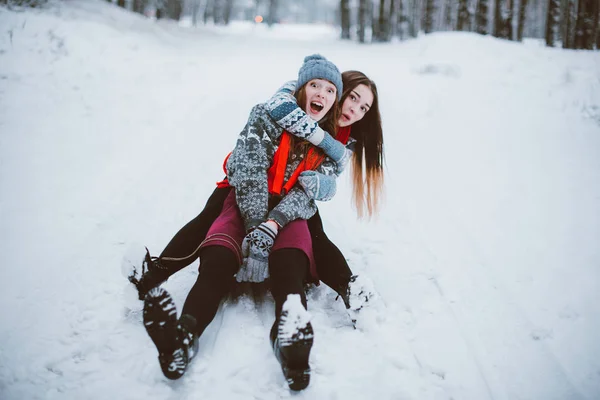 Dos jóvenes amigas adolescentes hipster juntos.Acercamiento retrato de moda de dos hermanas abrazos y divertirse, paseo en trineo en el bosque de invierno, usando suéteres y bufandas, mejores amigos pareja outdoo — Foto de Stock