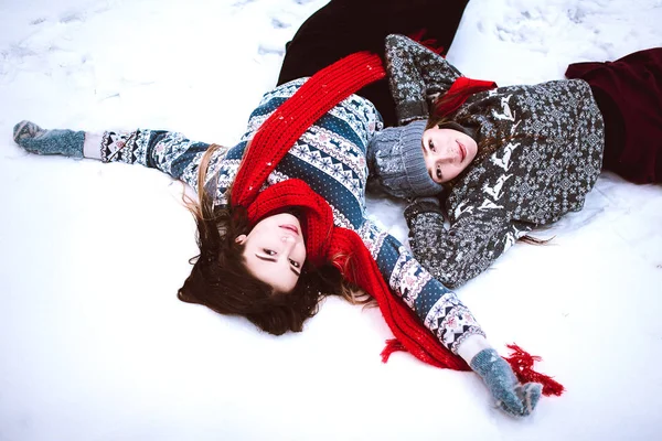 Dois jovens amigos hipster menina adolescente juntos.Close up retrato de moda de duas irmãs abraços e se divertindo mentir na neve na floresta tempo de inverno, vestindo camisolas e lenços, melhores amigos casal ao ar livre — Fotografia de Stock