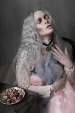 Karanlık halloween bir sandalyede oturuyor ve kalpleri toplayarak korkunç kötü zombi kız portresi. Kavramsal fotoğraf