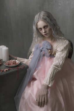 Karanlık halloween bir sandalyede oturuyor ve kalpleri toplayarak korkunç kötü zombi kız portresi. Kavramsal fotoğraf