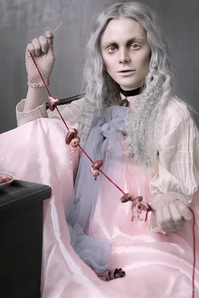 Karanlık halloween bir sandalyede oturuyor ve kalpleri toplayarak korkunç kötü zombi kız portresi. Kavramsal fotoğraf