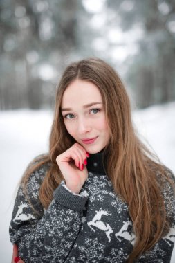 Winter portrait of young beautiful brunette woman wearing sweater. Snowing winter beauty fashion concept. clipart