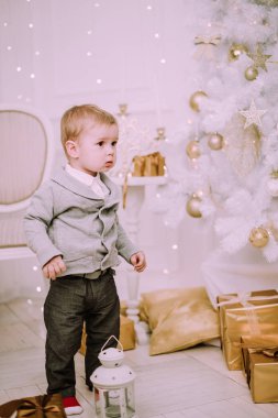 Hediyeler ile oynayan neşeli küçük oğlu ve Noel ağacı, altın ve bej pastel c sunar