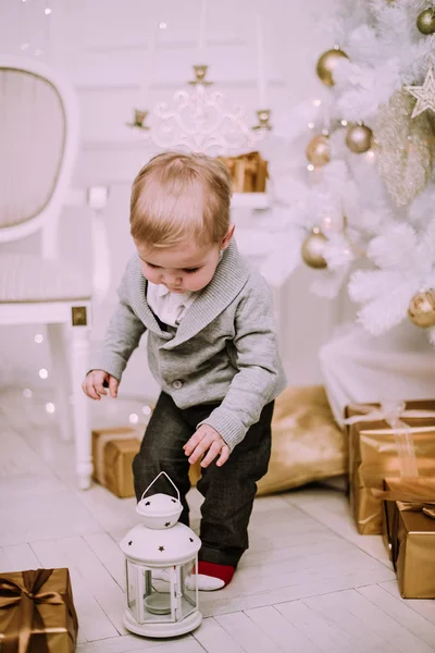 Alegre menino brincando com presentes e presentes perto da árvore de Natal, ouro e pastel bege c — Fotografia de Stock