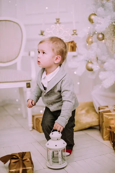 Niño alegre jugando con regalos y regalos cerca del árbol de Navidad, oro y pastel beige c — Foto de Stock