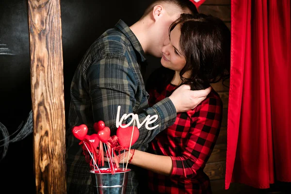 Молодая веселая европейская пара, влюбленная, обнимающаяся в будке поцелуев, украшенная студией сердец на День Святого Валентина, встречающаяся . — стоковое фото