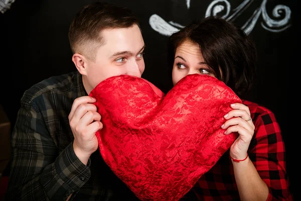 Joven pareja europea alegre en el amor abrazar y besar, en decorado con corazones estudio en día de San Valentín, citas . —  Fotos de Stock