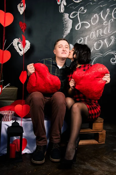 Joven pareja europea alegre en el amor abrazar y besar, en decorado con corazones estudio en día de San Valentín, citas . —  Fotos de Stock