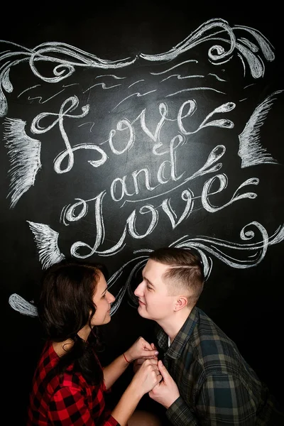 Mladý veselá Evropský pár v lásce objímat a líbat, v zdobené srdce studio na Valentýna, Seznamka. — Stock fotografie