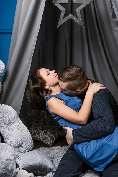 Young cheerful european couple in love embracing and kissing, in decorated with hearts studio on valentine day, dating. — Stock Photo, Image